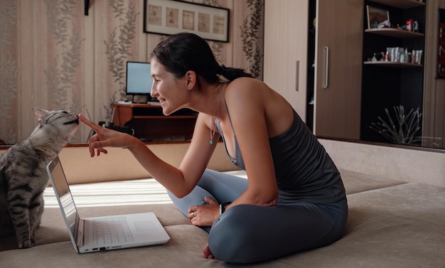 Jonge aantrekkelijke glimlachende vrouw die yoga beoefent terwijl ze in Halve Lotus-oefening zit