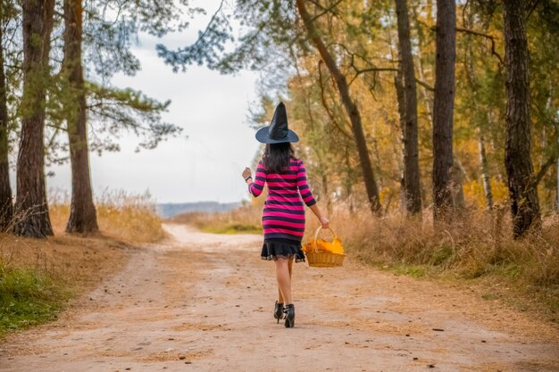 Jonge aantrekkelijke heks loopt in het herfst oranje forest.helloween concept.