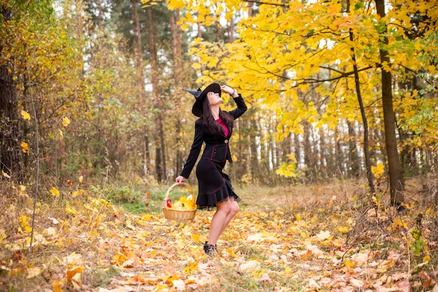Jonge aantrekkelijke heks loopt in het herfst oranje foresthelloween concept