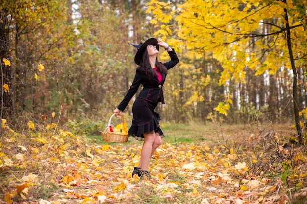 Jonge aantrekkelijke heks loopt in het herfst oranje foresthelloween concept