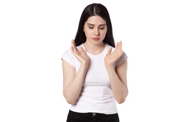 Jonge aantrekkelijke kaukasische zwartharige brunette vrouw in wit t-shirt, handen omhoog, gestrest, proberen kalm vrouw concept idee te houden