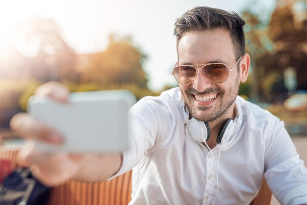 Foto jonge aantrekkelijke man lacht terwijl hij een koptelefoon draagt