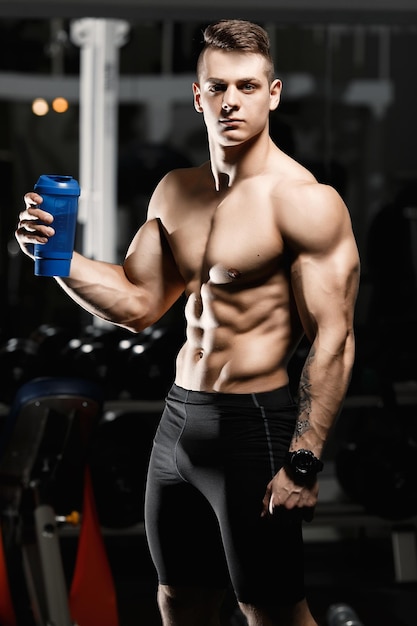 Jonge aantrekkelijke mannelijke bodybuilder toont spieren in de sportschool De atleet Professional Light
