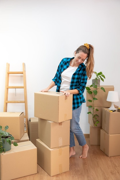 Jonge aantrekkelijke vrouw blij kartonnen dozen inpakken in een nieuw huis. Nieuwe huissleutels, nieuw leven.