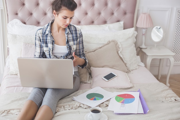 Jonge aantrekkelijke vrouw die bij laptop werkt