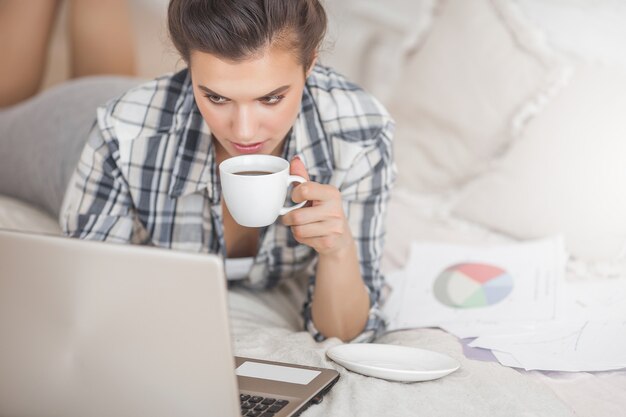 Jonge aantrekkelijke vrouw die bij laptop werkt