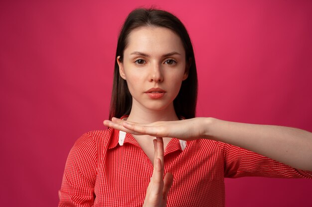 Jonge aantrekkelijke vrouw die een afwijzingsgebaar toont op een roze achtergrond