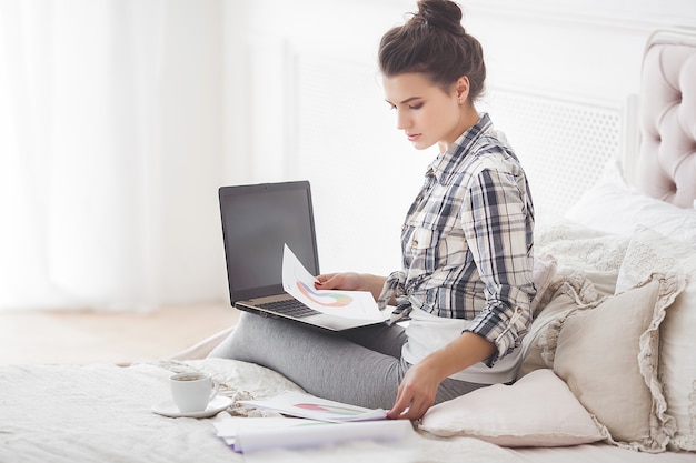 Jonge aantrekkelijke vrouw die naar huis bij laptop werkt