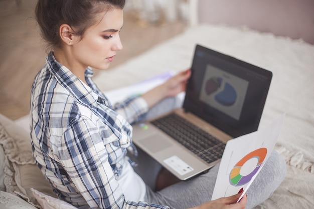 Jonge aantrekkelijke vrouw die naar huis bij laptop werkt