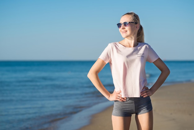 Jonge aantrekkelijke vrouw die ochtendoefeningen op het strand doet