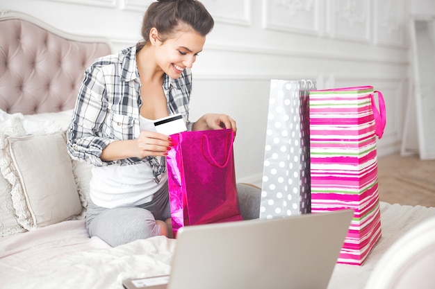 Jonge aantrekkelijke vrouw die thuis online winkelen maakt