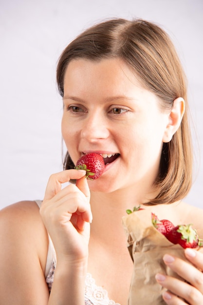 Jonge aantrekkelijke vrouw die verse rijpe aardbei eet