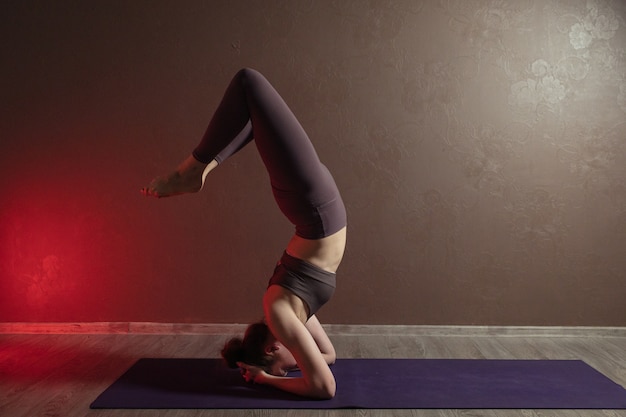 Jonge aantrekkelijke vrouw die yoga beoefent die sportkleding draagt