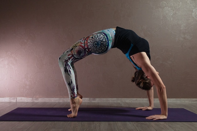 Jonge aantrekkelijke vrouw die yoga beoefent die sportkleding draagt