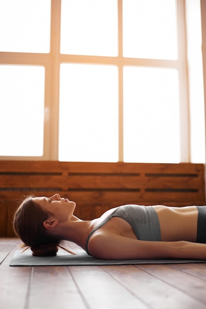 Jonge aantrekkelijke vrouw die yoga beoefent Savasana pose