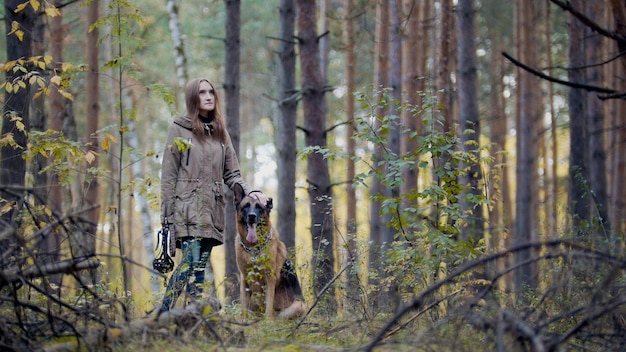 Jonge aantrekkelijke vrouw en haar huisdier Duitse herder wandelen op een herfstbos