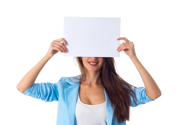 Jonge aantrekkelijke vrouw in blauwe jas die de helft van haar gezicht verbergt achter een wit vel papier