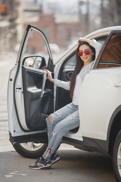 Jonge aantrekkelijke vrouw in de auto. Vrouw bestuurt een auto. Sluit omhoog portret van mooie vrouw in openlucht. Stedelijke dame.