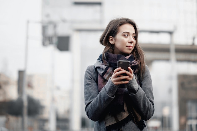 jonge aantrekkelijke vrouw in de stad heeft een telefoon in haar handen, sociaal netwerk