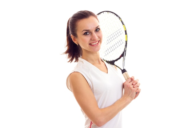 Jonge aantrekkelijke vrouw in wit sportshirt met donkere paardenstaart met tennisracket in studio