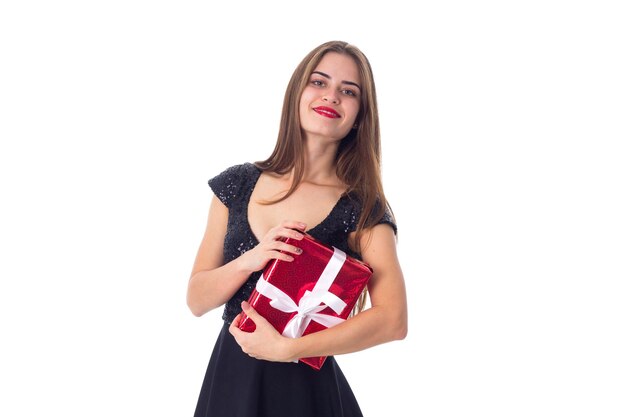 Jonge aantrekkelijke vrouw in zwarte jurk met rood cadeau met wit lint en opzoeken in studio