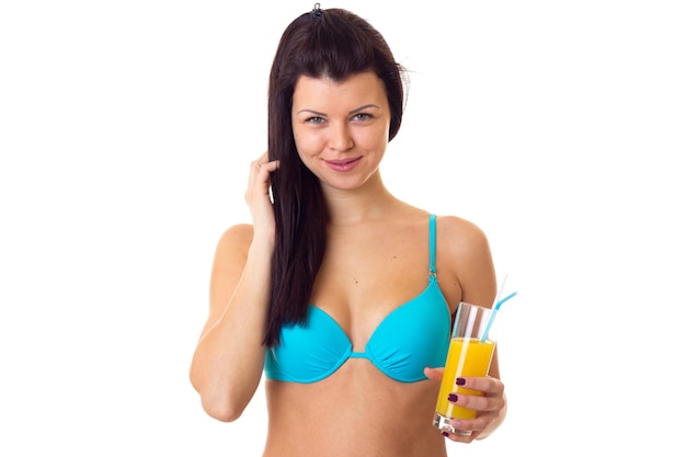 Jonge aantrekkelijke vrouw met lang donker haar in blauw zwempak met gele cocktail in studio