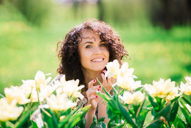 Jonge aantrekkelijke vrouw met lang krullend haar poseren in lente bloeiende tuin, appelbomen