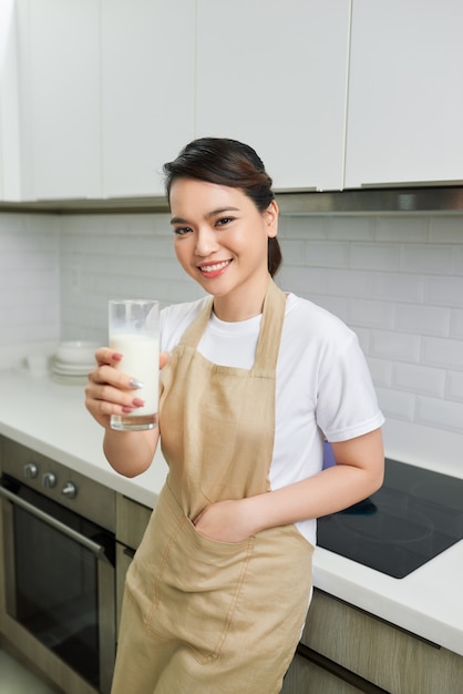 Jonge aantrekkelijke vrouw met melk en gezond ontbijt in keuken