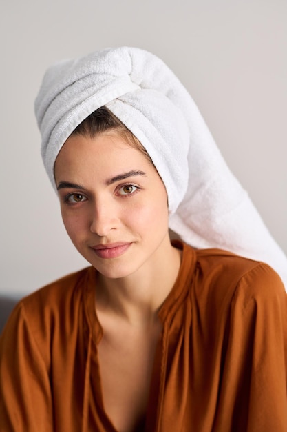 Jonge aantrekkelijke vrouw met zachte witte handdoek op hoofd na bad
