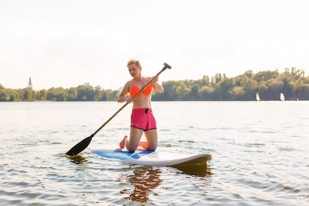 Jonge aantrekkelijke vrouw op stand-up paddle board in het meer, SUP