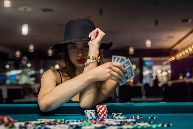 Jonge aantrekkelijke vrouw pokeren aan tafel met stapels chips en kaarten