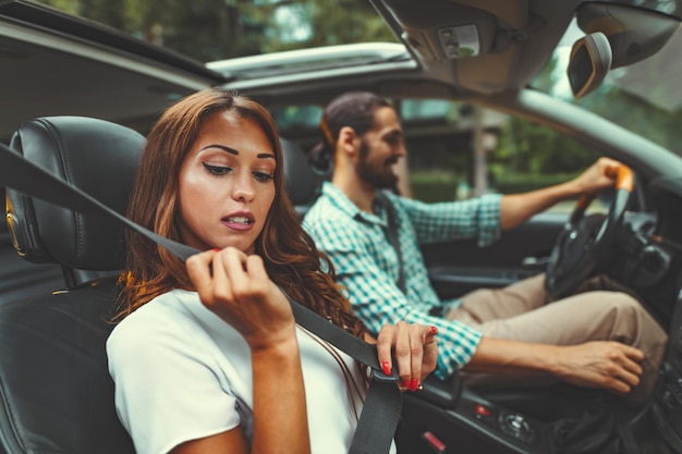 Jonge aantrekkelijke vrouw trekt aan de veiligheidsgordel in de auto.