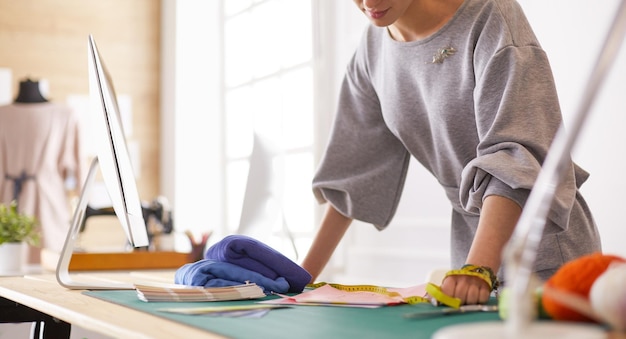 Jonge aantrekkelijke vrouwelijke modeontwerpers die op een bureau leunen en met een laptop werken