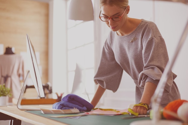 Jonge aantrekkelijke vrouwelijke modeontwerpers die op een bureau leunen en met een laptop werken