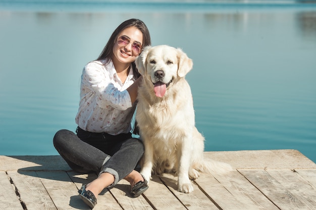 Jonge aantrekkelijke vrouwenzitting bij de pijler met haar hond. Beste vrienden buitenshuis