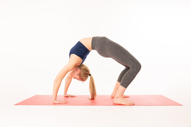 Jonge aantrekkelijke yogivrouw die yoga beoefent, die zich uitstrekt in Urdhva Dhanurasana-oefening