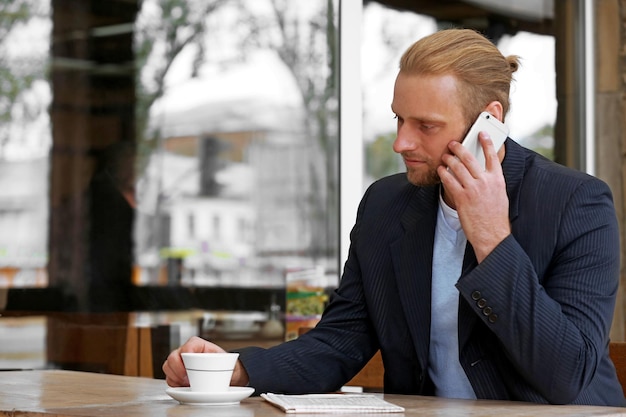 Jonge aantrekkelijke zakenman die lunch heeft en in een koffie werkt