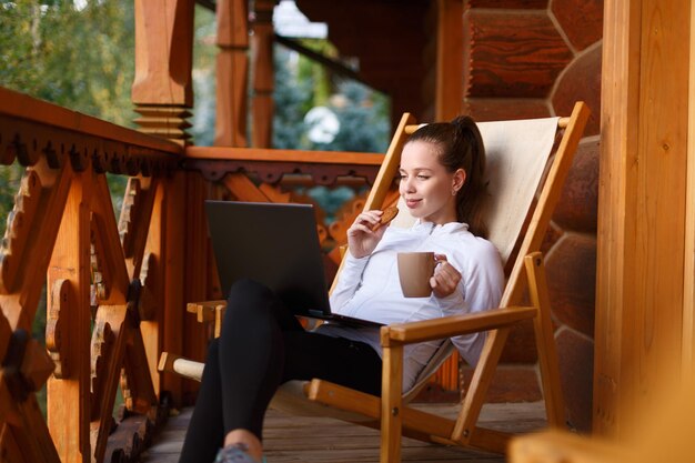 Jonge aantrekkelijke zakenvrouw werkt op de laptop in het bergresort met een kopje thee en