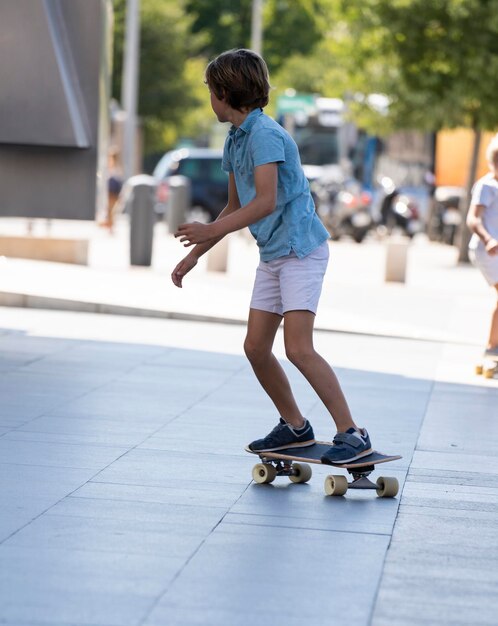 Jonge actieve elegante stijlvolle jongen balanceren op een skateboard in het centrum van Madrid