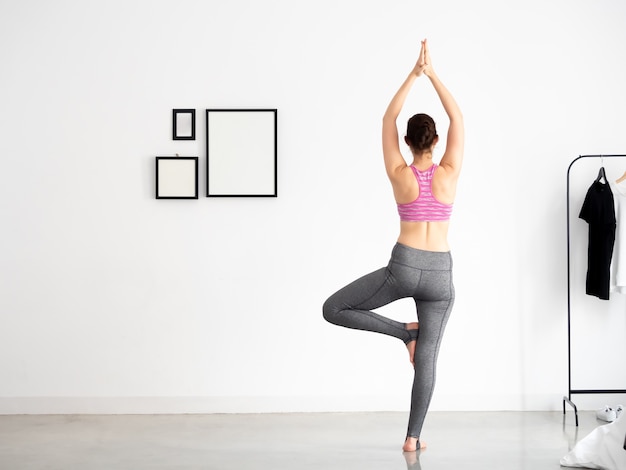 Jonge actieve vrouw in sportieve slijtage die yogapositie doet