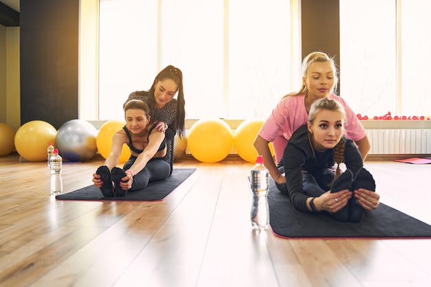 Foto jonge actieve vrouwen met een slank lichaam die rekoefening doen om fitte lichaamsflexibiliteit op yogamat te houden