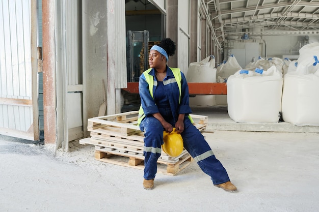 Jonge afgeleid afro-amerikaanse vrouwelijke ingenieur zittend op stapel pallets