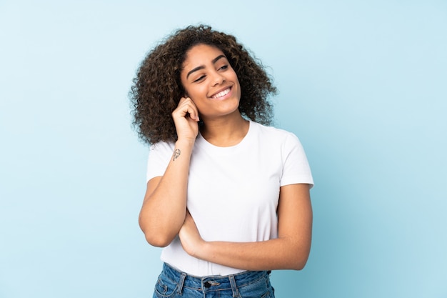 Jonge African American vrouw op blauwe muur lachen