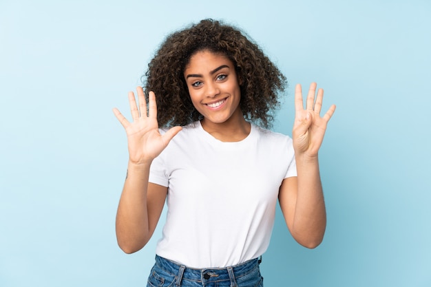 Jonge African American vrouw op blauwe muur tellen negen met vingers