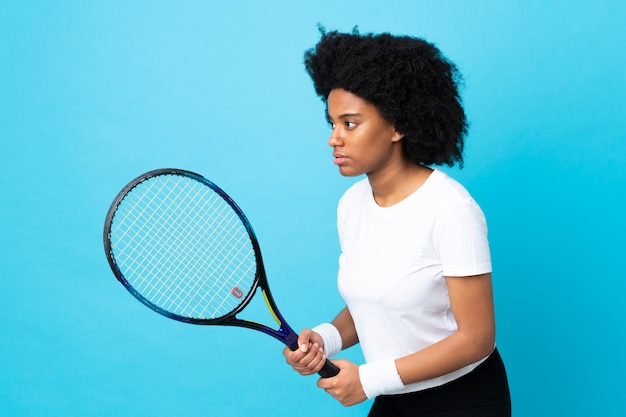 Jonge African American vrouw op blauwe muur tennissen