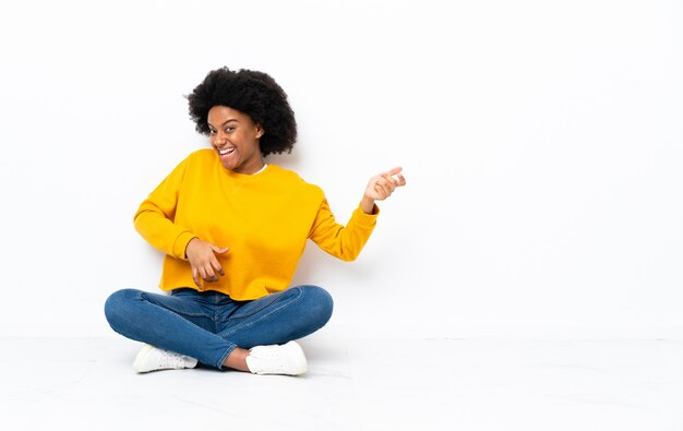 Jonge African American vrouw zittend op de vloer gitaar gebaar maken