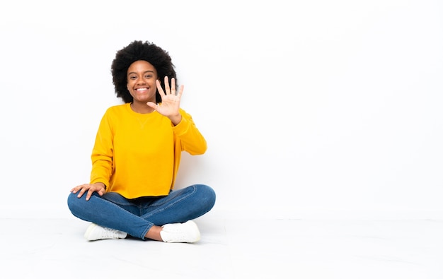 Jonge African American vrouw zittend op de vloer tellen vijf met vingers