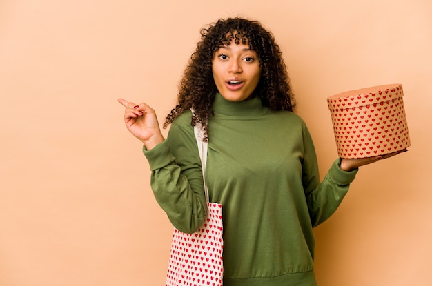 Jonge afrikaanse amerikaanse afrovrouw die een gift van de valentijnskaartendag houdt die naar de kant richt