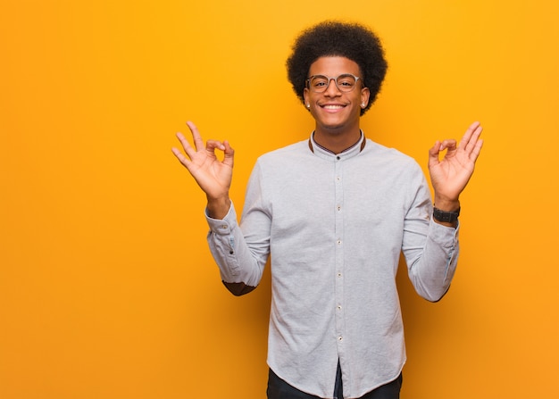 Jonge afrikaanse amerikaanse mens over een oranje muur die yoga uitvoert