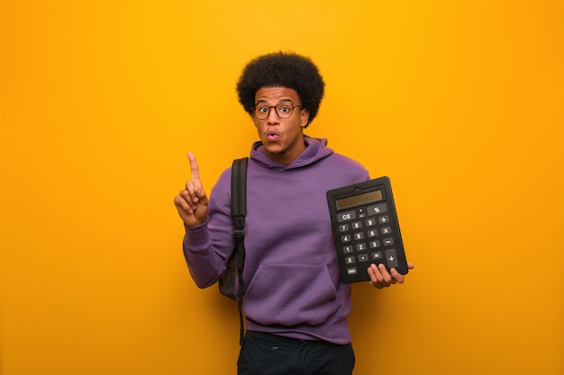 Jonge Afrikaanse Amerikaanse studentenmens die een calculator houdt die een groot idee heeft